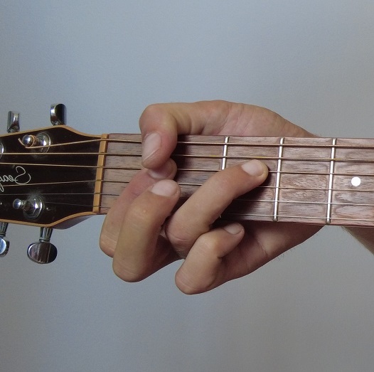 Photo d'une main faisant un accord de Fa mineur à la Hendrix à la guitare